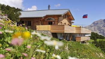 Aussenanischt des Sareis Bergrestaurant mit Blumen im Vordergrund und Bergen im Hintergrund