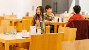 Gäste sitzen im hellen Café-Bereich des Kunstmuseums und unterhalten sich