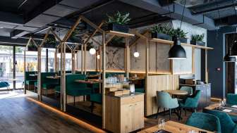 Modernes Restaurant mit stilvoller Holzkonstruktion, grünen Polstersitzen und kreativer Raumaufteilung