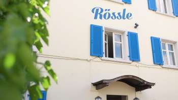 Außenansicht des Restaurant Rössle mit blauen Fensterläden und gemütlichem Eingangsbereich.